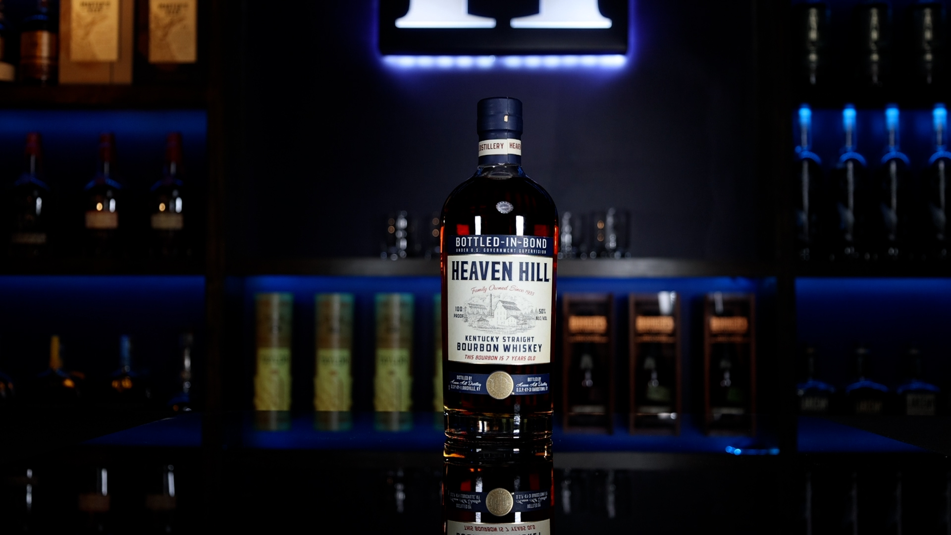 A bottle of Heaven Hill Bottled-in-Bond 7 Year whiskey sits on a table with a Homebar.io logo sign in the background.