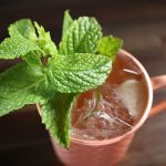 A Kentucky Mule Cocktail sits atop a dark-stained butcherblock surface.