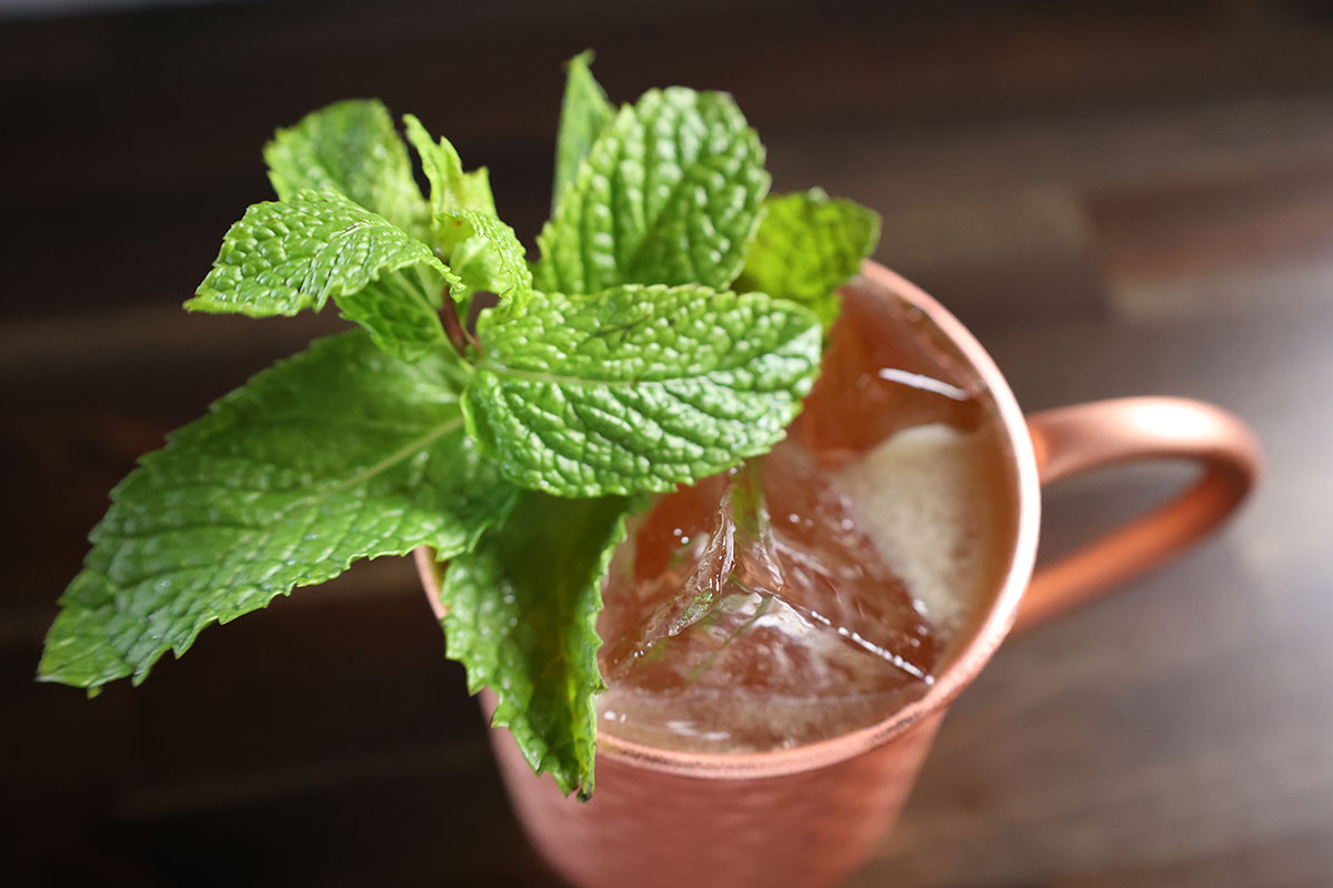 A Kentucky Mule Cocktail sits atop a dark-stained butcherblock surface.