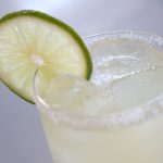 A Margarita cocktail sits atop a white counter with a lime wheel garnish.
