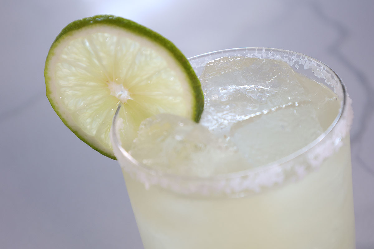 A Margarita cocktail sits atop a white counter with a lime wheel garnish.