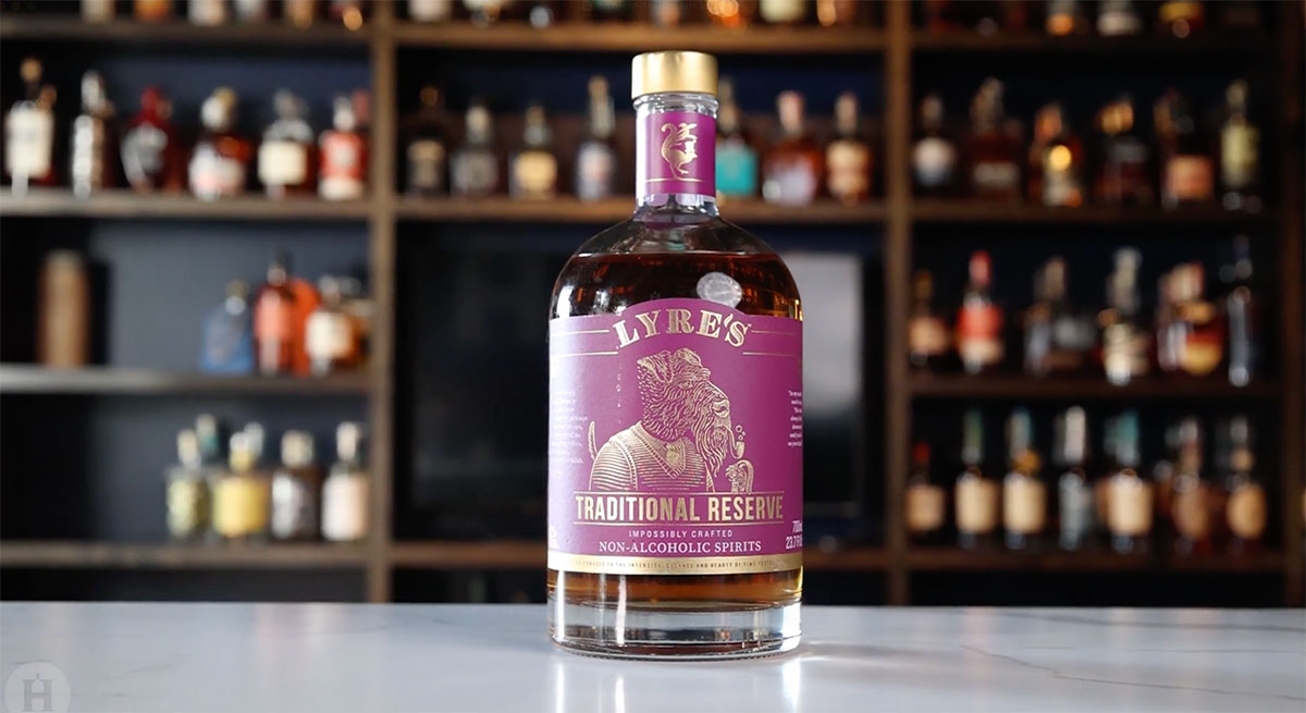 A bottle of Lyre's Traditional Reserve Whiskey Alternative sits on a bar top in front of shelves of bottles.