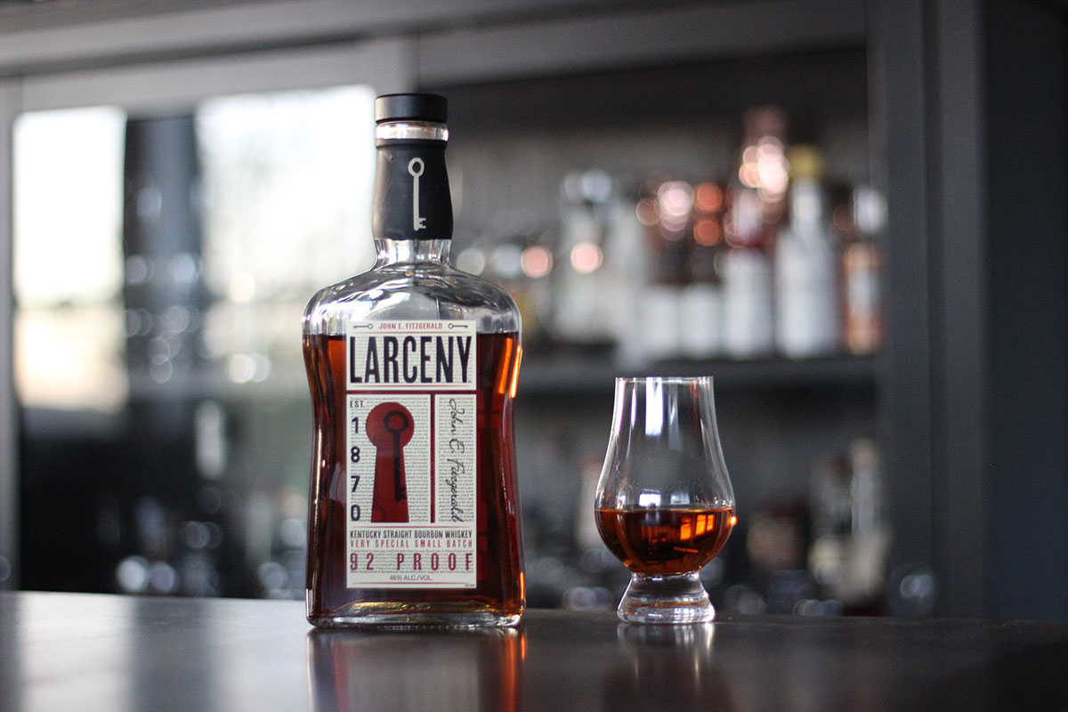 A bottle of Larceny Small Batch sits next to a Glencairn tasting glass with an ounce of Larceny in it.